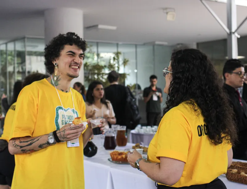 Participantes de camiseta amarela conversam durante o café.