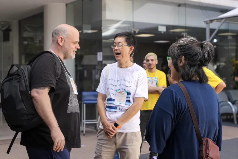 Grupo de participantes conversa em frente à entrada do evento.